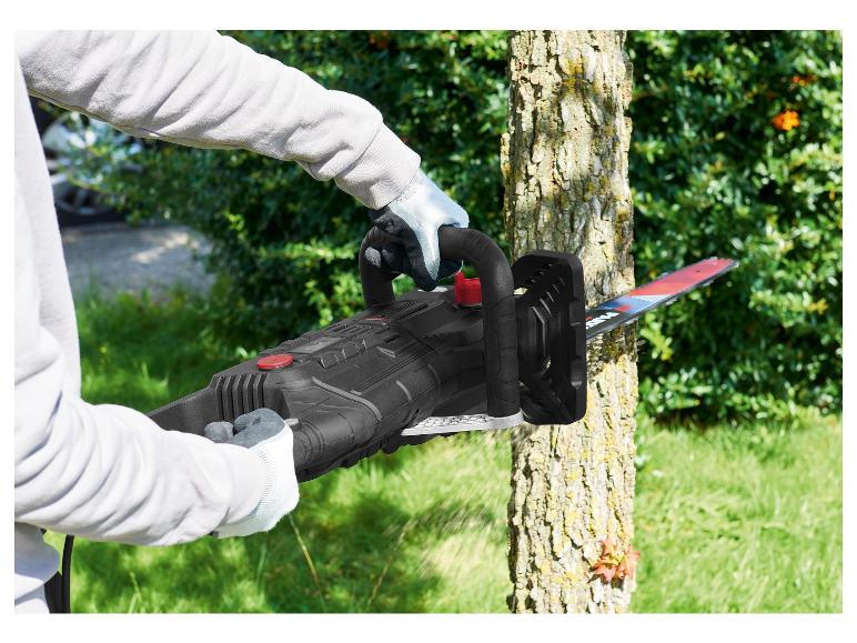Een persoon die een elektrische kettingzaag gebruikt om een boom te snoeien.