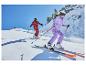 Deux skieurs en combinaisons de ski colorées et casques descendent une pente enneigée.