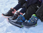Drie paar zwarte winterschoenen met blauwe en roze details in de sneeuw.