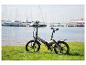 Vélo électrique pliant Sachsengrad sur l'herbe au bord d'un lac avec des yachts.