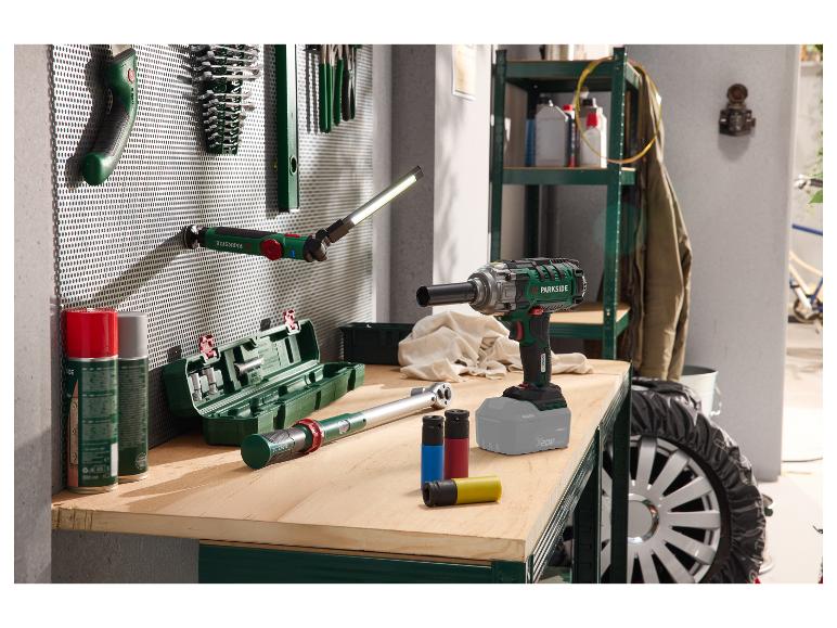 Clé à chocs, clé dynamométrique et lampe de travail sur un établi dans un garage.