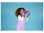 Une fillette en robe lilas tient un jouet papillon.