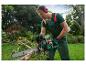 Man in groene overall zaagt boomtak met een Parkside kettingzaag.