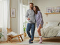 Un couple en pyjama, l'homme portant un haut gris et un pantalon bleu, la femme en pyjama à carreaux.