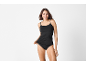 Vrouw in zwarte spaghettibandjes top en slip lachend naar de camera.