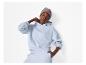 Femme en sweat à capuche et pantalon de survêtement bleu clair, avec un bonnet gris.