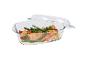 Glazen ovenschaal met deksel, met zalm, asperges en citroen.