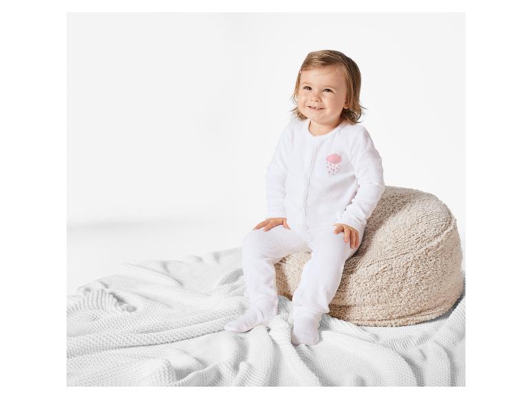 Een baby die op een pluche kussen zit, draagt een wit onesie met een regenwolkontwerp.