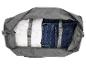 Open grijze reistas met wit overhemd en blauwe jeans