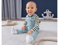 Een baby in een blauwe overall en een gestreepte trui