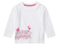 T-shirt blanc avec un imprimé d'un bus à impériale rouge avec des fleurs et des ballons.