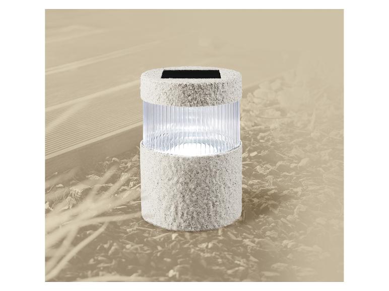 Lampe de jardin solaire avec finition grise texturée, éclairant un chemin de jardin.