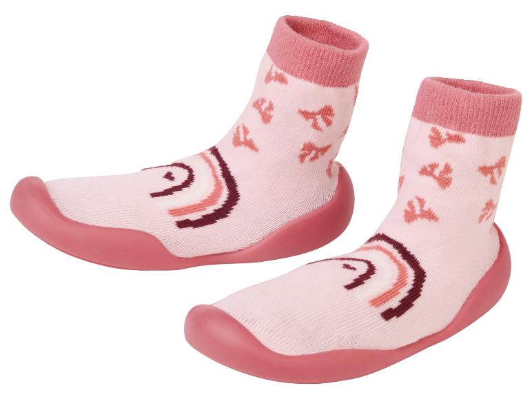 Een paar roze babysokken met rubberen zooltjes.