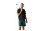 Man in een zwart t-shirt en groene korte broek, met een squashracket en een bal.