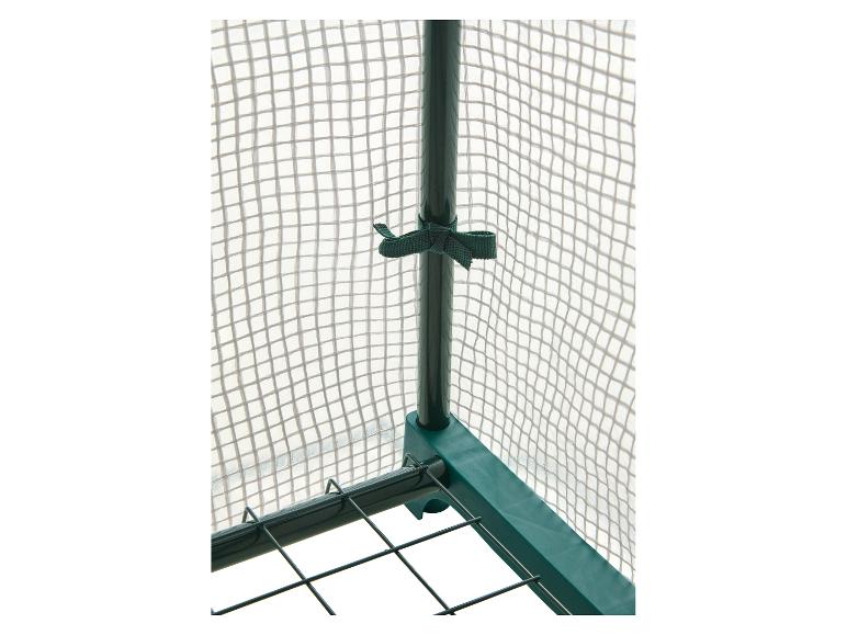 Detail van tuinkas met groen frame en transparante gaasafdekking.