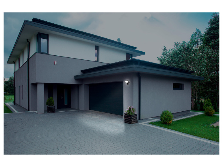 Une maison moderne avec un portail de garage et une lumière extérieure