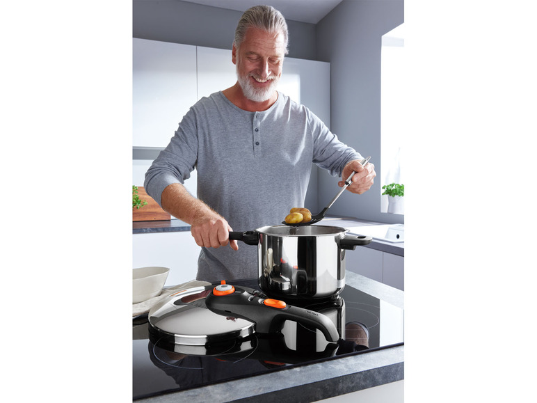 Un homme cuisine des pommes de terre dans une cocotte-minute Tefal sur une plaque à induction.