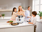 Een gezin kookt samen met een witte multicooker en een aantal accessoires.