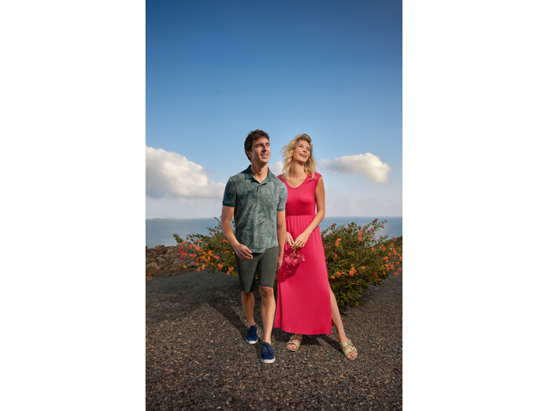 Man in poloshirt en korte broek, vrouw in lange jurk, beiden lachend buiten.