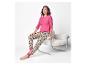 Femme souriante en pyjama rose et imprimé léopard, assise sur une chaise.