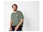 Man in groen T-shirt met 'Summer Surf'-opdruk en zwarte broek.
