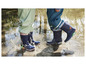 Deux enfants portent des bottes de pluie bleues avec des lumières dans une flaque.