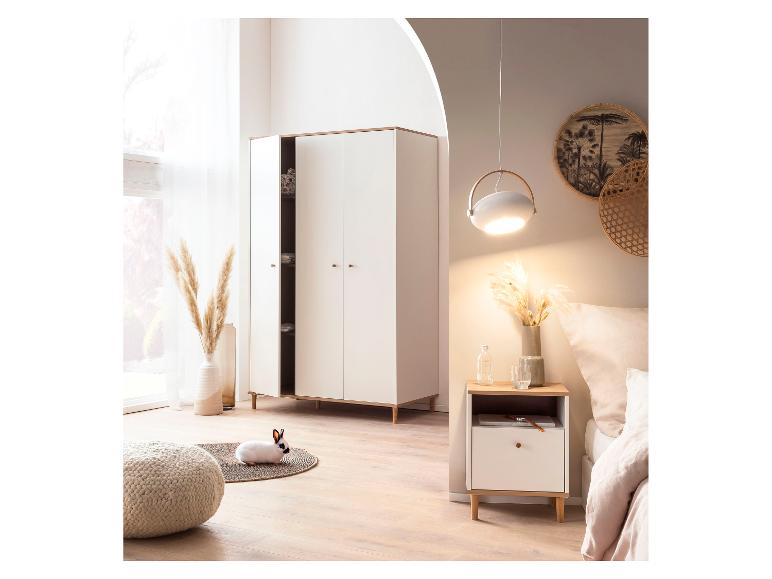 Slaapkamer met witte kledingkast, nachtkastje, bed en een konijn op een kleed.