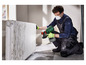 Un homme peint un radiateur avec un pistolet de peinture Parkside.