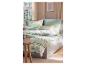 Bed met gestreept beddengoed in groen- en beigetinten, met een houten nachtkastje.