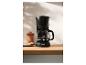 Zwart filterkoffiezetapparaat met vers gezette koffie in een moderne keuken.