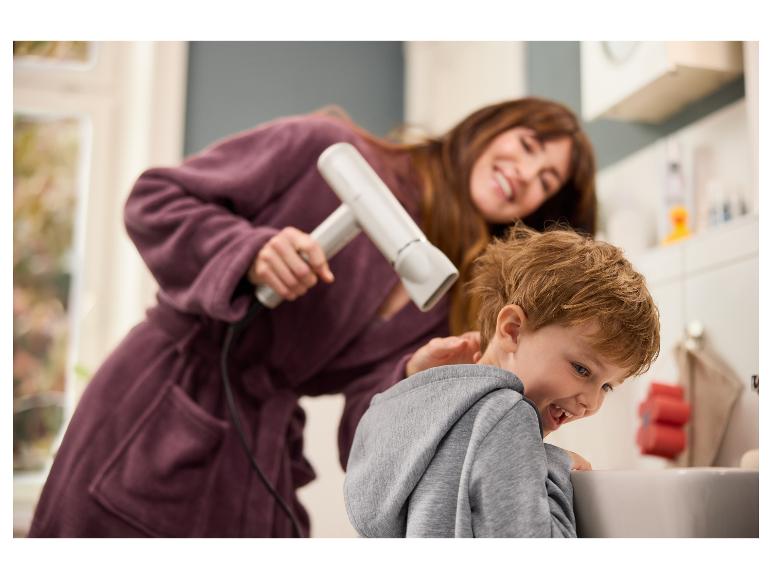 Une femme sèche les cheveux d'un garçon avec un sèche-cheveux.