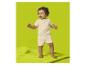 Bébé en ensemble chemise à manches courtes et short couleur crème, debout sur un tapis vert.