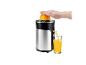 Presse-agrumes en acier inoxydable avec une orange et du jus frais dans un verre