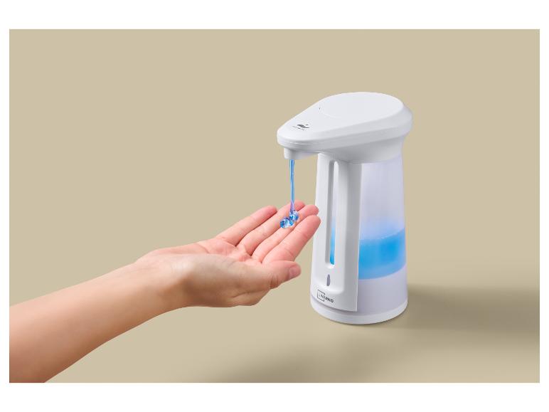 Een hand ontvangt zeep uit een automatische dispenser met blauwe vloeistof.