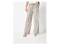 Vrouw draagt beige wijde broek en witte sandalen met hak.