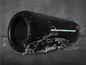 Un haut-parleur Bluetooth portable noir résistant à l'eau, arrosé d'eau.