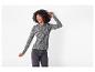 Lachende vrouw in een luipaardprint top met lange mouwen en jeans.