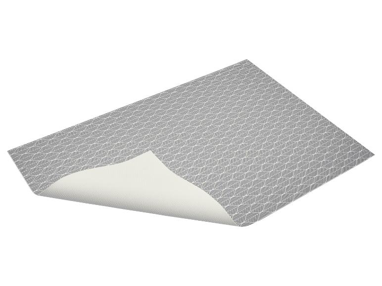Grijze placemat met bladpatroon, licht opgetild aan één hoek.