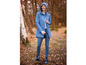 Une femme avec un imperméable bleu et des bottes bleues se tient dans une forêt.