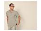 Man met bril, lichtgroen poloshirt en beige korte broek, lachend en opzij kijkend.