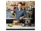 Jamie Oliver cuisine des pâtes dans une cuisine avec des murs en briques et des comptoirs en marbre.