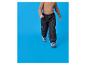 Pantalon matelassé noir pour enfant et pull marron sur fond bleu.