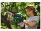 Femme rousse utilisant une tronçonneuse sans fil Parkside pour élaguer un arbre.