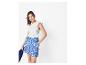 Vrouw in wit T-shirt met ruches en blauwe bedrukte shorts