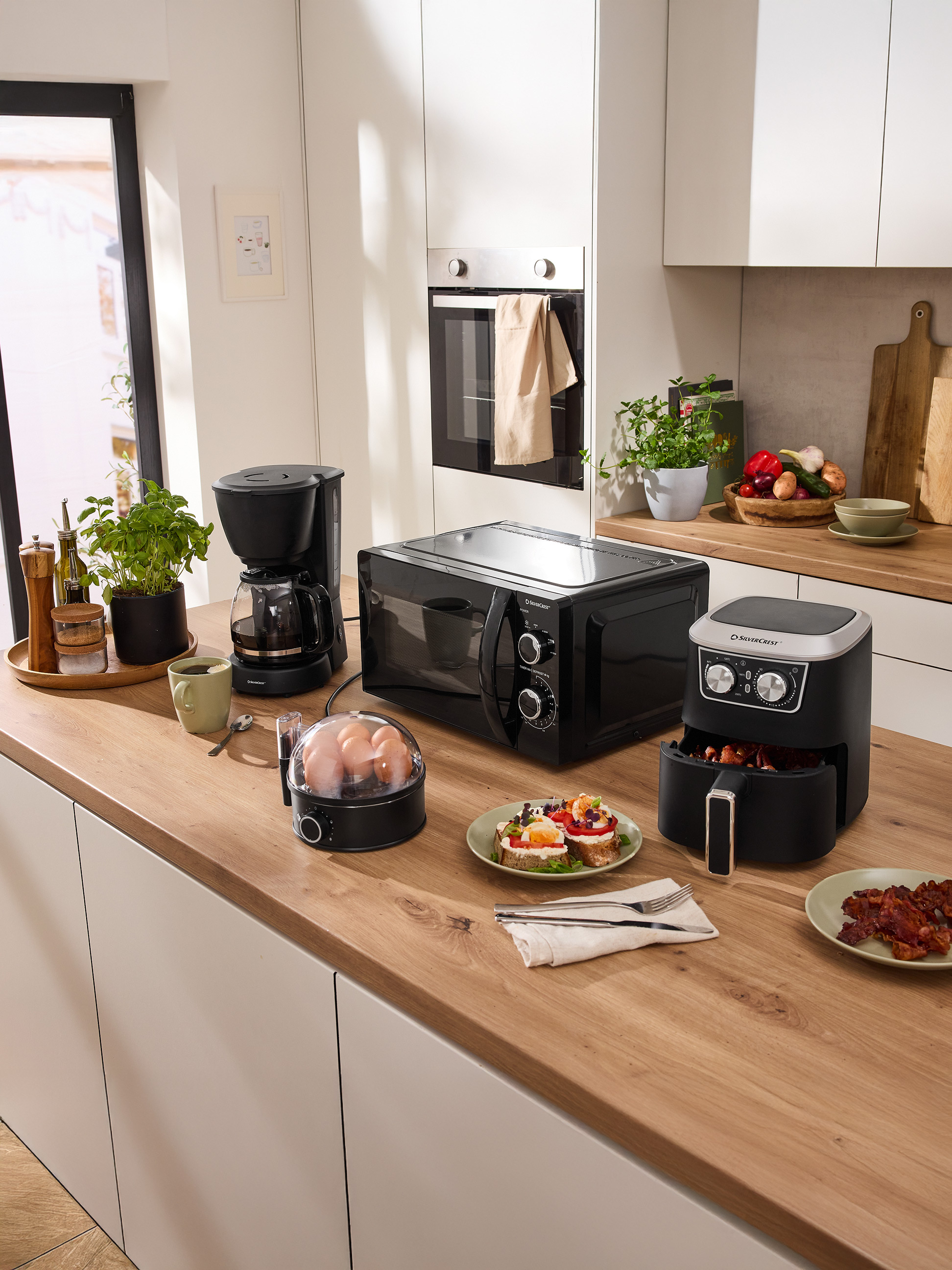 Keukenblad met SilverCrest magnetron, koffiezetapparaat, airfryer en ontbijtapparaten.