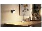 Een wandlamp en een kleine bureaulamp verlichten een houten bureau.