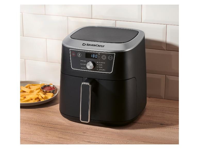 Friteuse à air noire avec affichage numérique 180°C, à côté d'une assiette de frites et de ketchup.