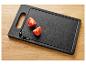 Deux moitiés de tomates cerises sur une planche à découper noire avec de l'huile