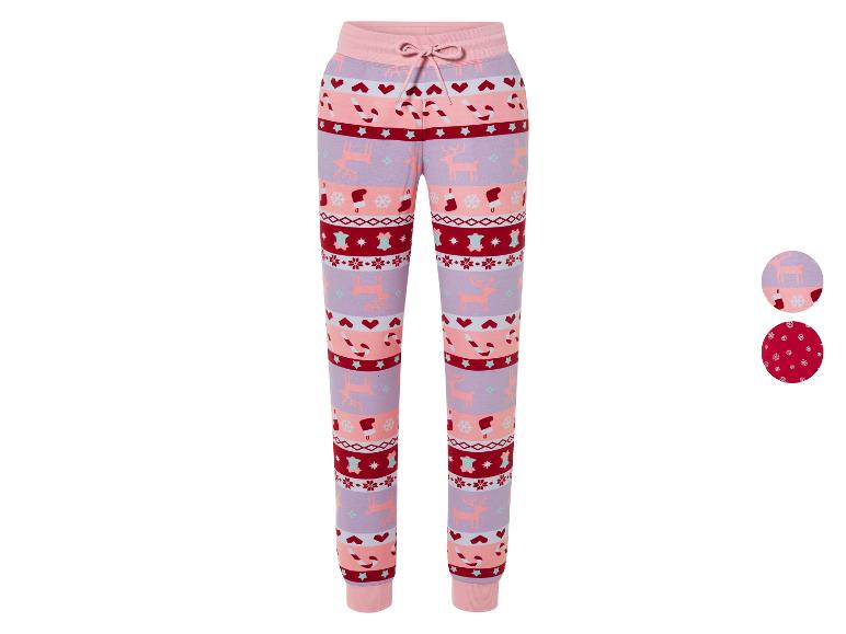 Un pantalon de survêtement rose sur le thème de Noël, décoré de rennes, de cannes en sucre et de flocons de neige.