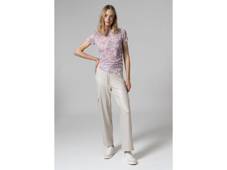 Vrouw draagt een T-shirt met print en witte broek.
